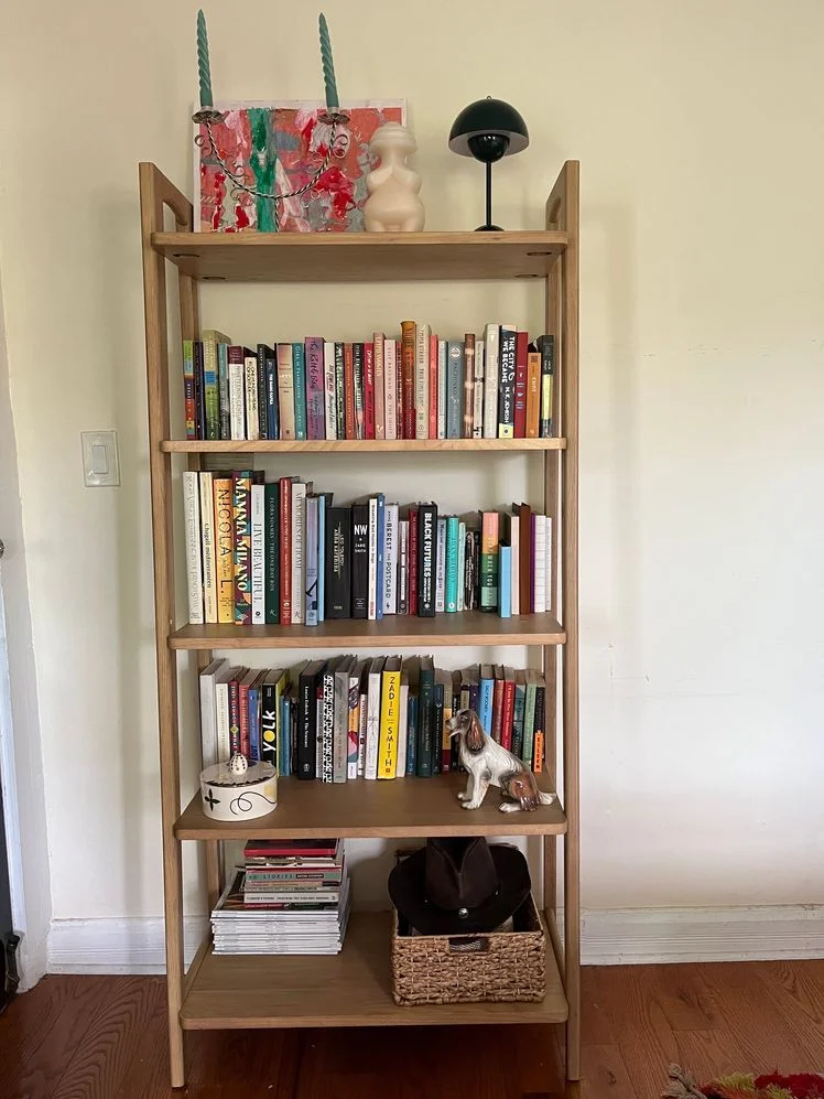 5-tier wooden bookshelf styled with assorted books, candles, sculptures, and art.