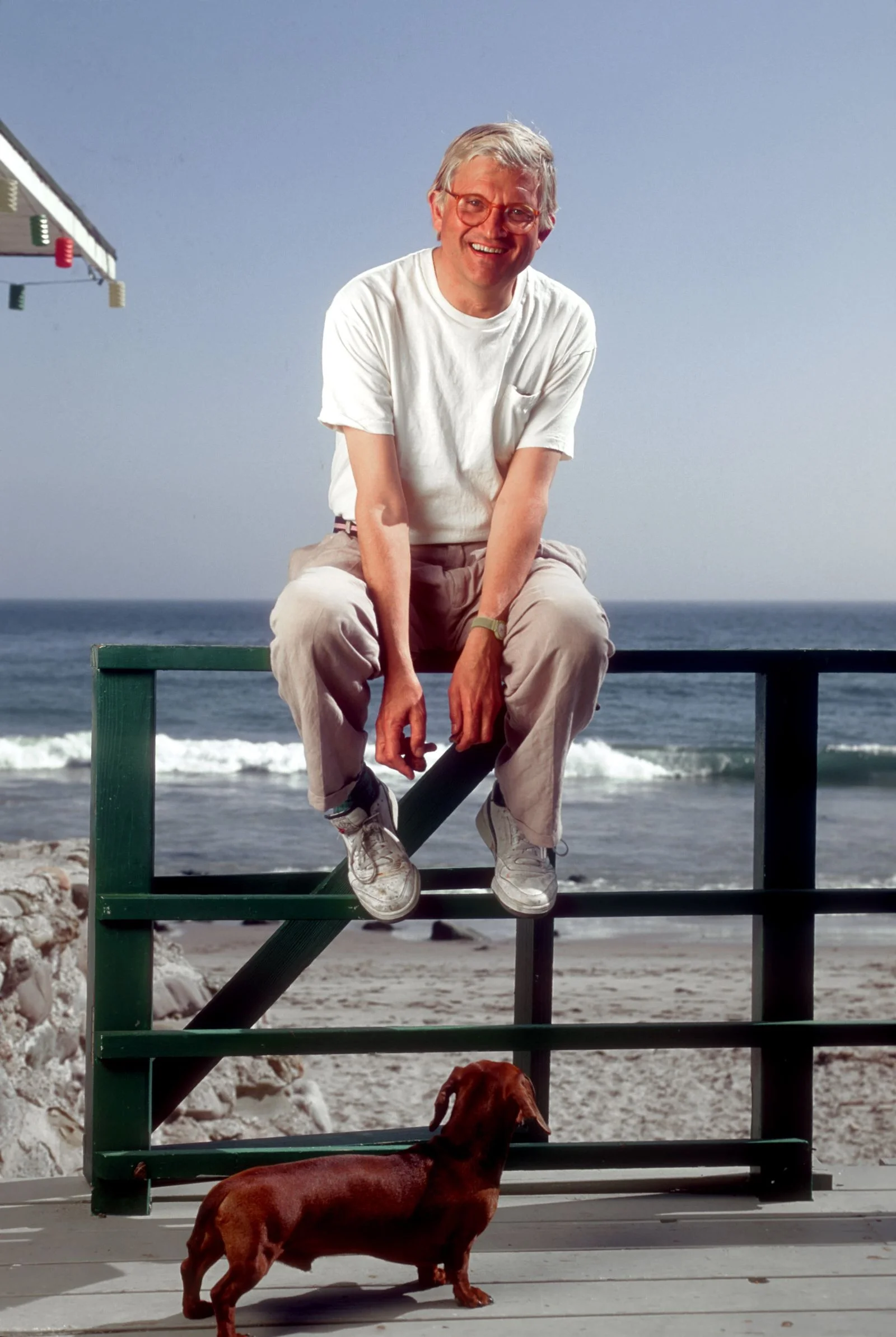 Image may contain David Hockney Person Sitting Adult Face Head Photography Portrait Beachwear Clothing and Pants