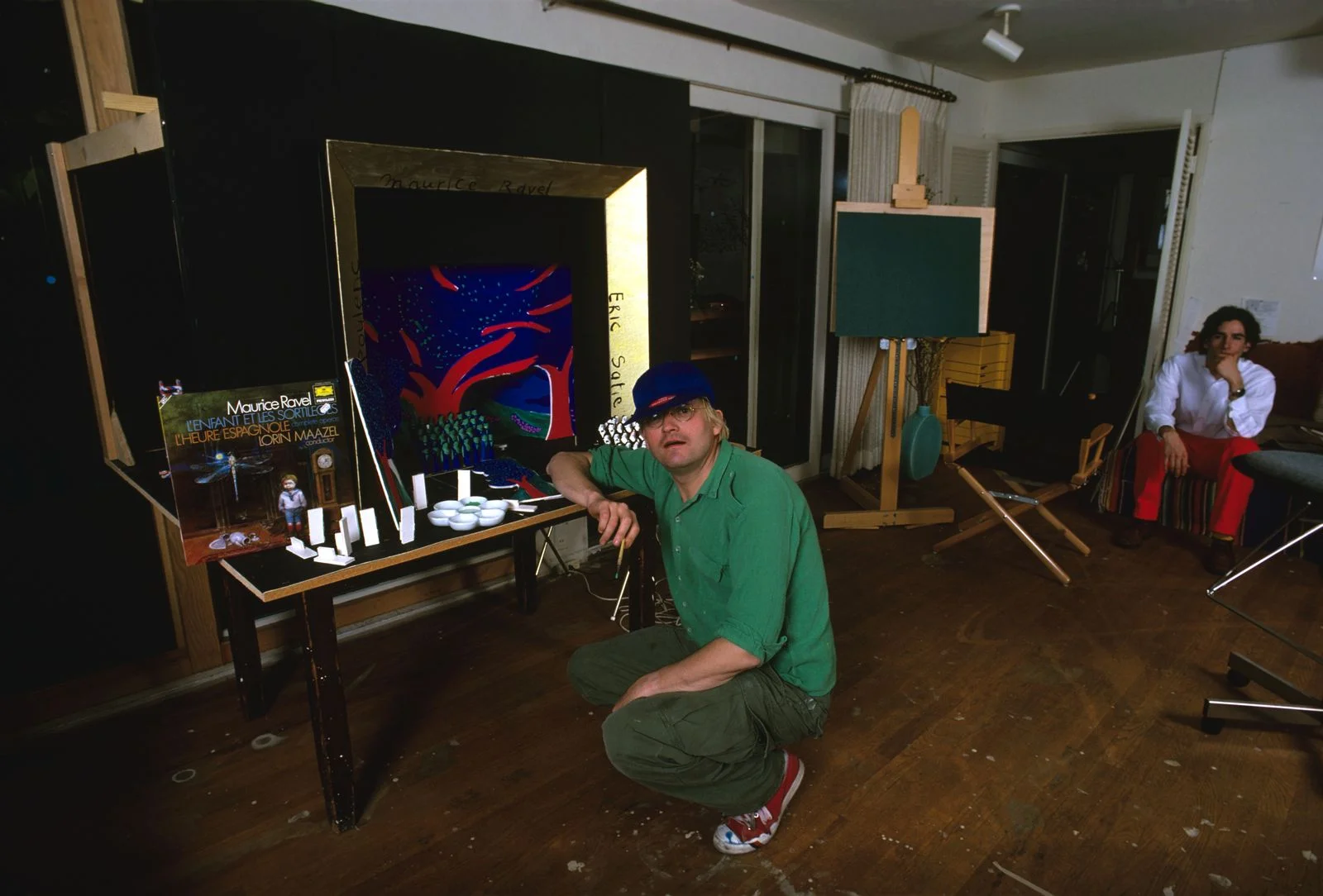 Image may contain David Hockney Face Head Person Photography Portrait Baseball Cap Cap Clothing Hat and Lamp