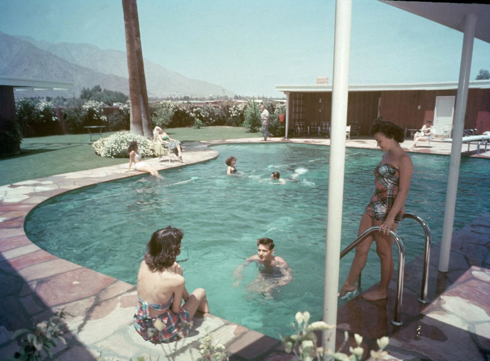 pianoshaped pool at Frank Sinatras Twin Palms home five swimmers more people seated poolside