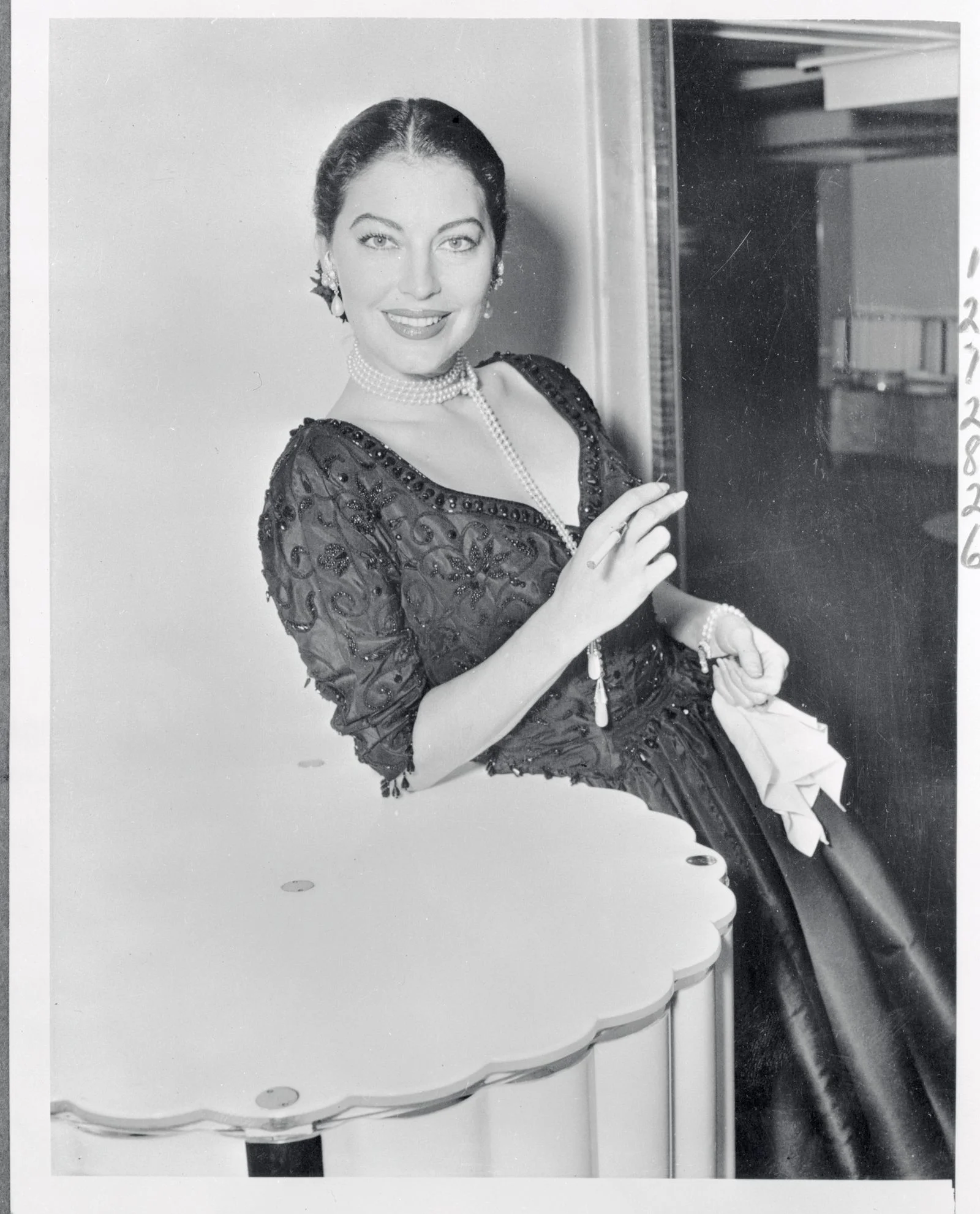 blackandwhite image of Ava Gardner in dark gown smiling holding cigarette
