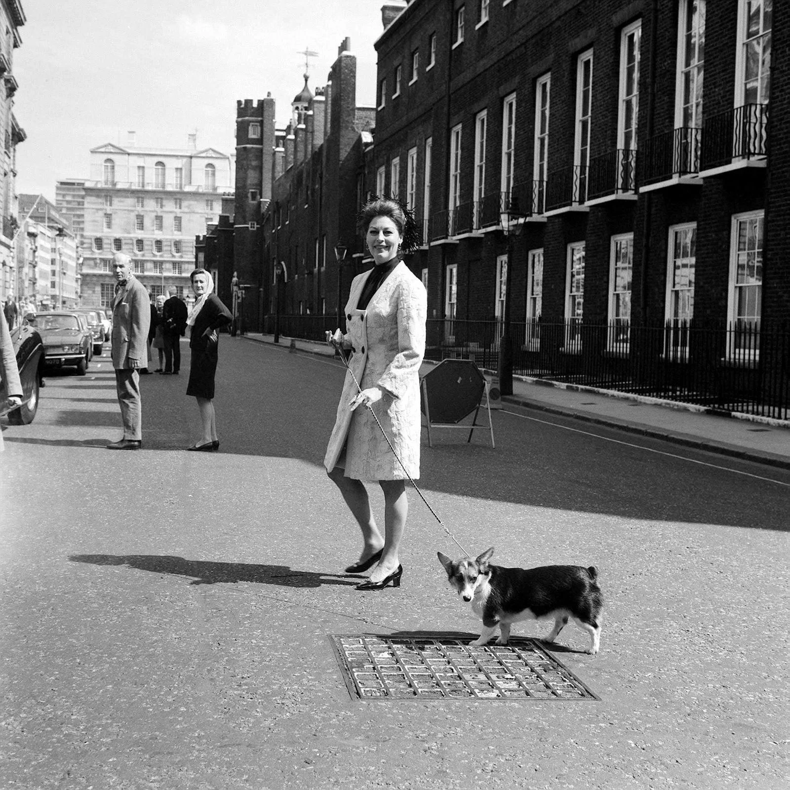 blackandwhite photo of Ava Gardner walking down London street with her Corgi