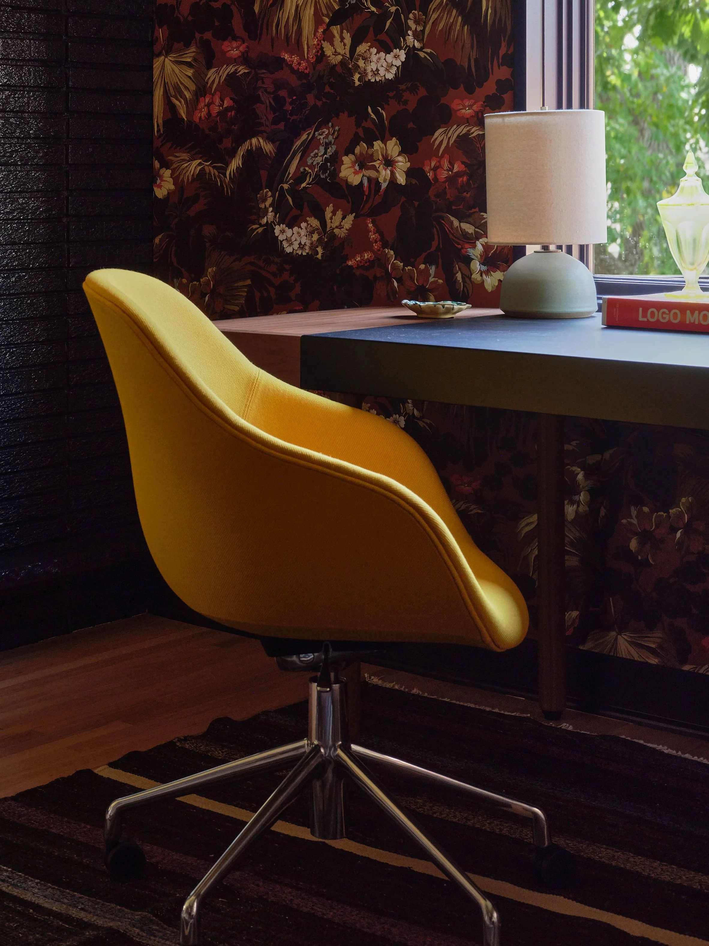 Home office with a fireplace and floral wallpaper.
