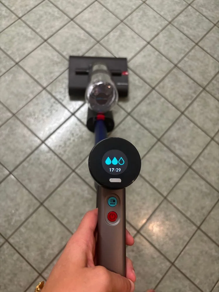 Person holding the Dyson WashG1 Wet Cleaner on a tile floor.