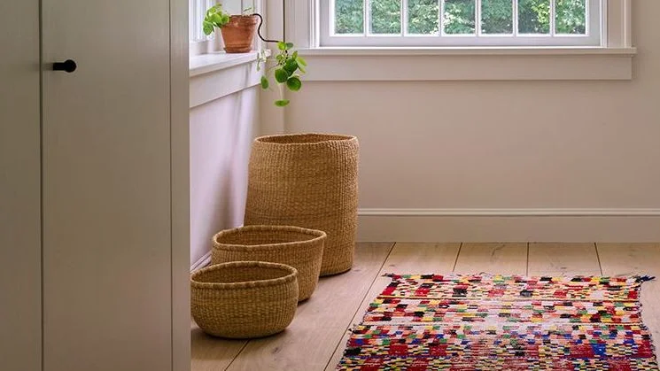 Bathroom with multicolored rug and three wicker storage baskets.