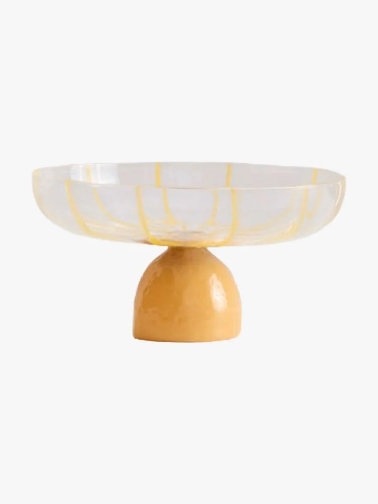 Glass pedestal bowl with yellow base and striped sides.