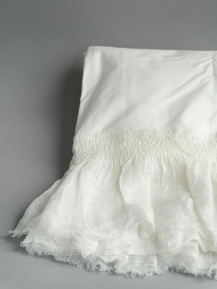 White sheet with ruffled edges.