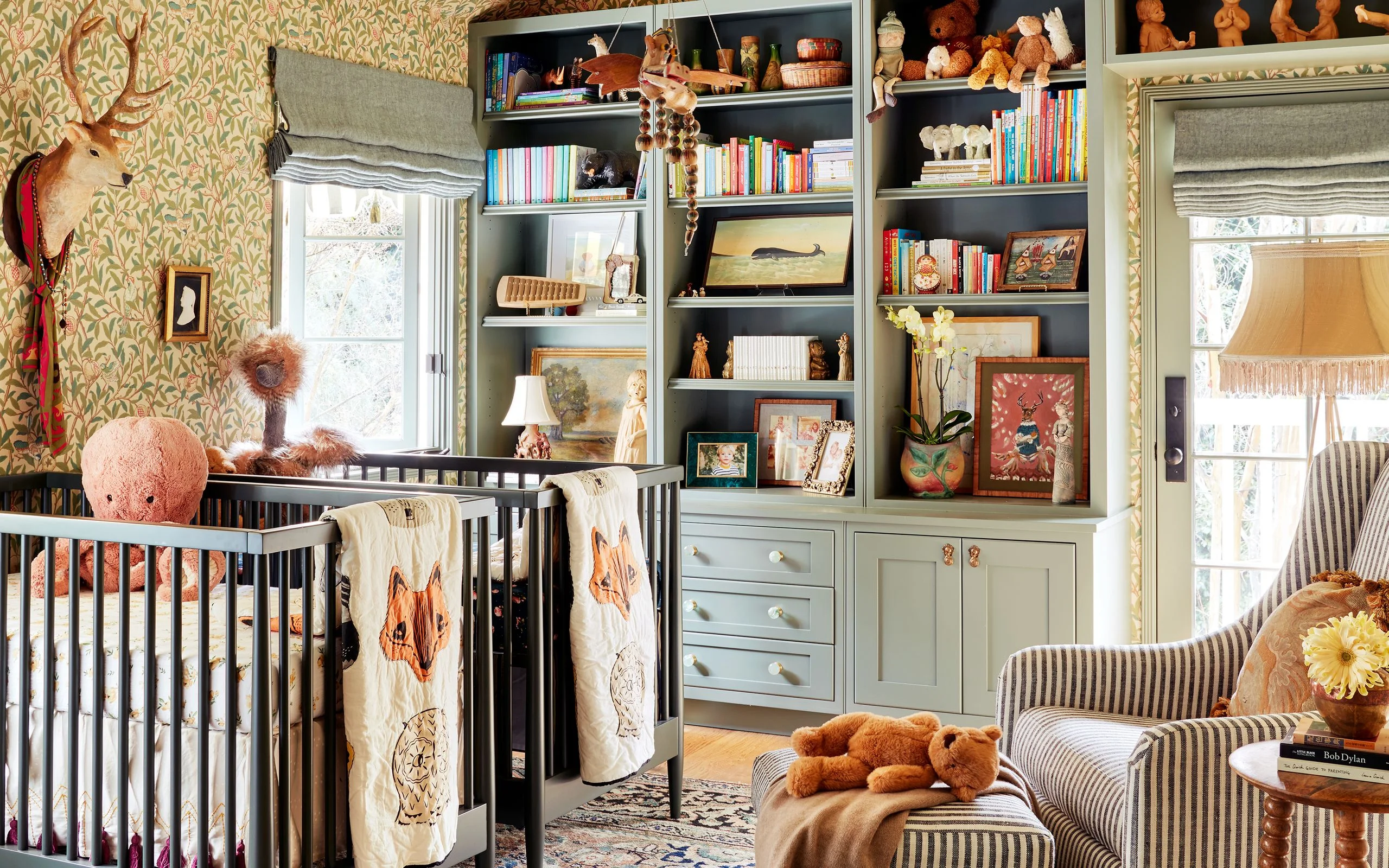Nursery with wallpaper and builtin toy storage bookshelves.